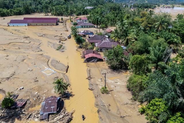 This picture shows an aerial view of villagers wading through the mudflow to find a shelter in the aftermath of flash floods in Tukka village, Central Tapanuli, North Sumatra province, on December 3, 2025. Officials in Indonesia and Sri Lanka battled on December 3 to reach survivors of deadly flooding in remote, cut-off regions as the toll in the disaster that hit four countries topped 1,300. In Indonesia, there is growing frustration among survivors of catastrophic flooding and landslides over the pace of the rescue effort and aid delivery. (Photo by YT Hariono / AFP)