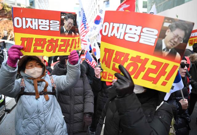Supporters of South Korea's ousted president Yoon Suk Yeol hold placards reading "Trial Lee Jae Myung!" as they march toward the ruling Democratic Party headquarters during a rally marking the first anniversary of Yoon's declaration of martial law, near the National Assembly in Seoul on December 3, 2025. South Korea's ousted former leader Yoon Suk Yeol issued a call from prison on December 3 urging his supporters to rally for "freedom" and defending his decision to declare martial law a year ago. (Photo by Jung Yeon-je / AFP)