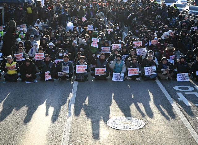 Members of the Korean Confederation of Trade Unions hold placards reading "Completely clear the insurrectionists!" during a rally marking the first anniversary of the declaration of martial law by ousted president Yoon Suk Yeol, in front of the National Assembly in Seoul on December 3, 2025. Yoon suspended civilian rule in South Korea on December 3, 2024, for the first time in more than four decades, prompting massive protests and a showdown in parliament. A year later, the country remains politically polarised as it faces a slowing economy and an ageing population, as well as the lingering threat from North Korea. (Photo by Jung Yeon-je / AFP)