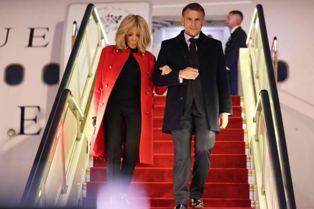 TOPSHOT - France's President Emmanuel Macron (R) and his wife Brigitte Macron disembark from their plane upon their arrival at the Capital International Airport in Beijing on December 3, 2025. French President Emmanuel Macron touched down on December 3 in China, an AFP journalist saw, where he is expected to put pressure on his counterpart Xi Jinping to help secure a ceasefire in Ukraine and discuss trade relations. (Photo by Ludovic MARIN / POOL / AFP)
