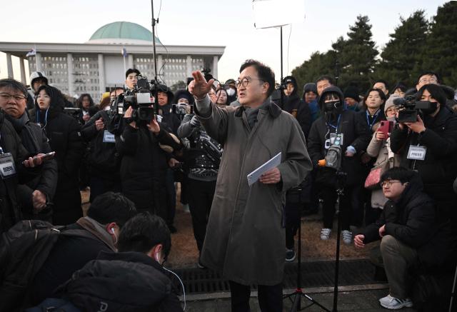 National Assembly Speaker Woo Won-shik (C) guides visitors during a dark tour on martial law sites to mark the first anniversary of the declaration of martial law by ousted president Yoon Suk Yeol, at the National Assembly in Seoul on December 3, 2025. Yoon suspended civilian rule in South Korea on December 3, 2024, for the first time in more than four decades, prompting massive protests and a showdown in parliament. A year later, the country remains politically polarised as it faces a slowing economy and an ageing population, as well as the lingering threat from North Korea. (Photo by JUNG YEON-JE / POOL / AFP)