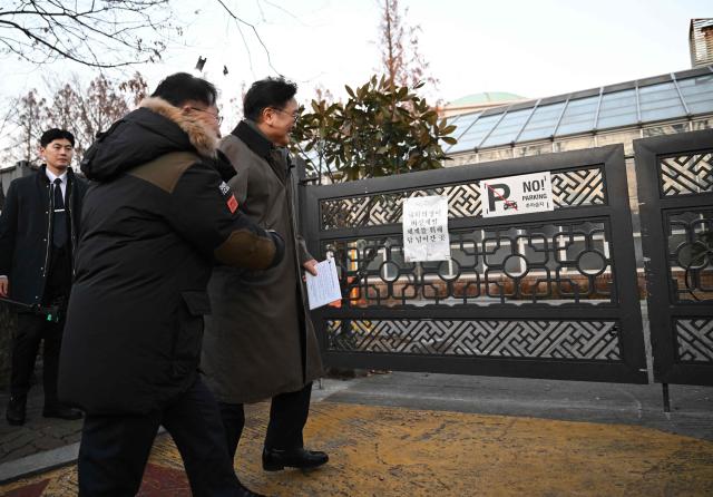 National Assembly Speaker Woo Won-shik (R) guides visitors as he walks along the wall he jumped over a year ago, during a dark tour on martial law sites to mark the first anniversary of the declaration of martial law by ousted president Yoon Suk Yeol, at the National Assembly in Seoul on December 3, 2025. Yoon suspended civilian rule in South Korea on December 3, 2024, for the first time in more than four decades, prompting massive protests and a showdown in parliament. A year later, the country remains politically polarised as it faces a slowing economy and an ageing population, as well as the lingering threat from North Korea. (Photo by JUNG YEON-JE / POOL / AFP)