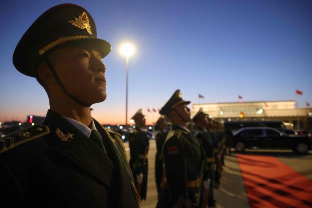 Chinese honour guards stand to attention during a ceremonial welcome for France's President Emmanuel Macron and his wife Brigitte Macron at the Capital International Airport in Beijing on December 3, 2025. French President Emmanuel Macron touched down on December 3 in China, an AFP journalist saw, where he is expected to put pressure on his counterpart Xi Jinping to help secure a ceasefire in Ukraine and discuss trade relations. (Photo by Ludovic MARIN / POOL / AFP)