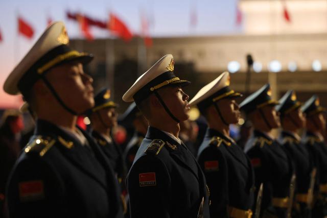 Chinese honour guards stand to attention during a ceremonial welcome for France's President Emmanuel Macron and his wife Brigitte Macron at the Capital International Airport in Beijing on December 3, 2025. French President Emmanuel Macron touched down on December 3 in China, an AFP journalist saw, where he is expected to put pressure on his counterpart Xi Jinping to help secure a ceasefire in Ukraine and discuss trade relations. (Photo by Ludovic MARIN / POOL / AFP)