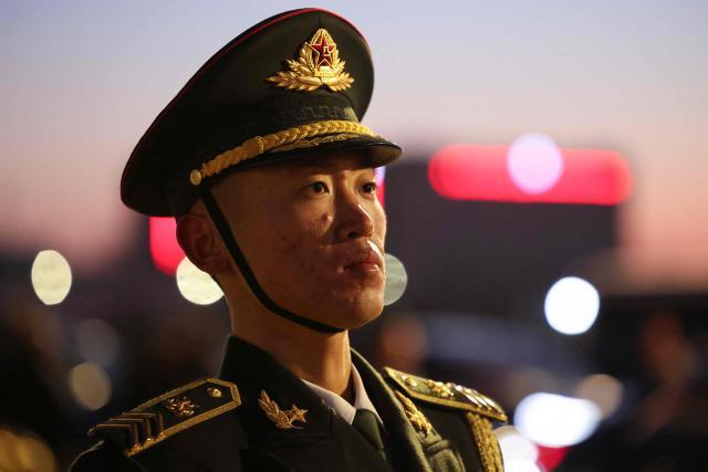A member of the Chinese honour guards stands to attention during a ceremonial welcome for France's President Emmanuel Macron and his wife Brigitte Macron at the Capital International Airport in Beijing on December 3, 2025. French President Emmanuel Macron touched down on December 3 in China, an AFP journalist saw, where he is expected to put pressure on his counterpart Xi Jinping to help secure a ceasefire in Ukraine and discuss trade relations. (Photo by Ludovic MARIN / POOL / AFP)
