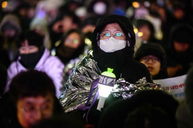 Protesters take part in a rally near the National Assembly in Seoul on December 3, 2025, to mark the first anniversary of the declaration of martial law by ousted president Yoon Suk Yeol. Yoon suspended civilian rule in South Korea on December 3, 2024, for the first time in more than four decades, prompting massive protests and a showdown in parliament. A year later, the country remains politically polarised as it faces a slowing economy and an ageing population, as well as the lingering threat from North Korea. (Photo by ANTHONY WALLACE / AFP)