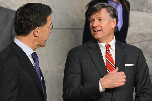 NATO Secretary General Mark Rutte (L) speaks with US Deputy Secretary of State Christopher Landau as they prepare for a group photo following a meeting of NATO Ministers of Foreign Affairs at NATO headquarters in Brussels on December 3, 2025. (Photo by NICOLAS TUCAT / AFP)