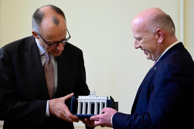 Berlin's mayor Kai Wegner (R) gives a model of the Brandenburg Gate to German Chancellor Friedrich Merz during his first official visit as Chancellor in the federal state of Berlin at the so-called Rotes Rathaus (Red City Hall) in the German capital, on December 3, 2025. (Photo by John MACDOUGALL / AFP)