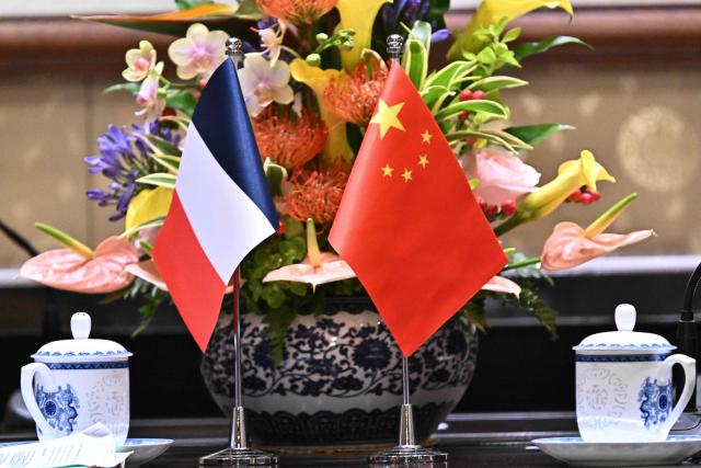 The flags of France (L) and China are seen during a meeting between France's Foreign Affairs Minister Jean-Noel Barrot and China's Foreign Minister Wang Yi at the Diaoyutai State Guesthouse in Beijing on December 3, 2025. French President Emmanuel Macron touched down on December 3 in China, an AFP journalist saw, where he is expected to put pressure on his counterpart Xi Jinping to help secure a ceasefire in Ukraine and discuss trade relations. (Photo by Pedro PARDO and Pedro Pardo / POOL / AFP)