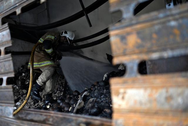 A firefighter tries to control a fire at the Rio de Janeiro State Food Distribution Center (CEASA) at Iraja neighborhood in Rio de Janeiro, Brazil on December 3, 2025. (Photo by MAURO PIMENTEL / AFP)