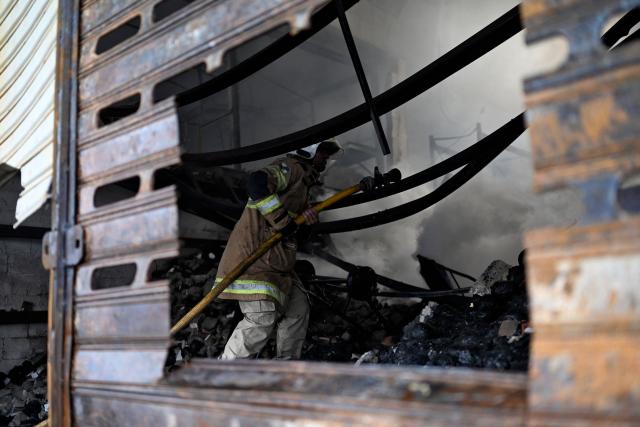 A firefighter tries to control a fire at the Rio de Janeiro State Food Distribution Center (CEASA) at Iraja neighborhood in Rio de Janeiro, Brazil on December 3, 2025. (Photo by MAURO PIMENTEL / AFP)