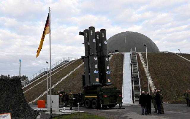 People stand in front of the Arrow 3 shield system during an event of the German Air Force to declare the Initial Operating Capability for the Arrow Weapon System for Germany at the Annaburger Heide Air Base in Schoenewalde / Holzdorf, eastern Germany, on December 3, 2025. The German military put the first parts of a roughly $4 billion Arrow 3 anti-missile shield system into service, aimed at bolstering Europe's air defences to counter Russian threats. The Arrow 3 shield system is part of the broader European Sky Shield effort launced in the wake of Russia's full-scale invasion of Ukraine, which raised alarm over possible gaps in NATO's European air defences. The German-Israeli deal to supply the Arrow 3 system inked in 2023 has been described as Israel's largest-ever military export contract. (Photo by RALF HIRSCHBERGER / AFP)