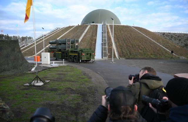 Photographers take pictures of the Arrow 3 shield system and a radar dome during an event of the German Air Force to declare the Initial Operating Capability for the Arrow Weapon System for Germany at the Annaburger Heide Air Base in Schoenewalde / Holzdorf, eastern Germany, on December 3, 2025. The German military put the first parts of a roughly $4 billion Arrow 3 anti-missile shield system into service, aimed at bolstering Europe's air defences to counter Russian threats. The Arrow 3 shield system is part of the broader European Sky Shield effort launced in the wake of Russia's full-scale invasion of Ukraine, which raised alarm over possible gaps in NATO's European air defences. The German-Israeli deal to supply the Arrow 3 system inked in 2023 has been described as Israel's largest-ever military export contract. (Photo by RALF HIRSCHBERGER / AFP)