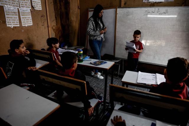 A young learner reads during the start of classes at Latin Patriarchate School inside the Holy Family Catholic Church compound sheltering displaced Palestinians in Gaza City, on December 3, 2025. Israel said on December 3, it would open the Rafah crossing from Gaza to Egypt to allow residents to exit the Palestinian territory "in the coming days," but Egypt denied such a deal with Israel. (Photo by Omar AL-QATTAA / AFP)