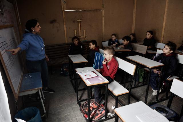 An educator instruct young learners during the start of classes at Latin Patriarchate School inside the Holy Family Catholic Church compound sheltering displaced Palestinians in Gaza City, on December 3, 2025. Israel said on December 3, it would open the Rafah crossing from Gaza to Egypt to allow residents to exit the Palestinian territory "in the coming days," but Egypt denied such a deal with Israel. (Photo by Omar AL-QATTAA / AFP)