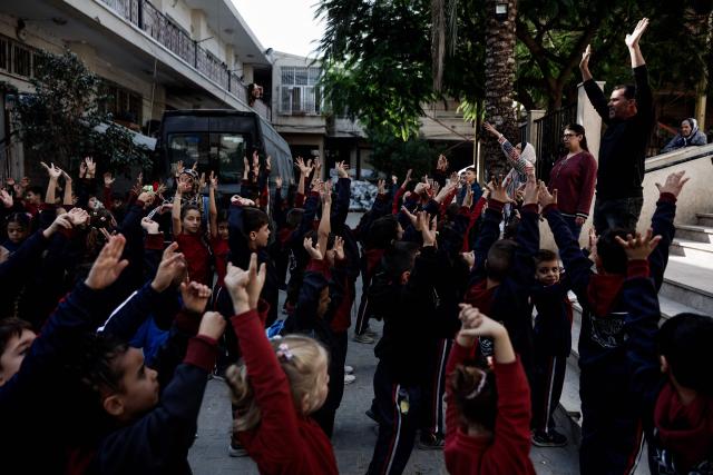 Young learners exercise during the start of classes at Latin Patriarchate School inside the Holy Family Catholic Church compound sheltering displaced Palestinians in Gaza City, on December 3, 2025. Israel said on December 3, it would open the Rafah crossing from Gaza to Egypt to allow residents to exit the Palestinian territory "in the coming days," but Egypt denied such a deal with Israel. (Photo by Omar AL-QATTAA / AFP)