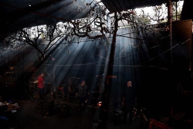 TOPSHOT - Displaced Palestinian prepare food on a fire in a shelter at the Holy Family Catholic Church compound in Gaza City, on December 3, 2025. Israel said on December 3, it would open the Rafah crossing from Gaza to Egypt to allow residents to exit the Palestinian territory "in the coming days," but Egypt denied such a deal with Israel. (Photo by Omar AL-QATTAA / AFP)