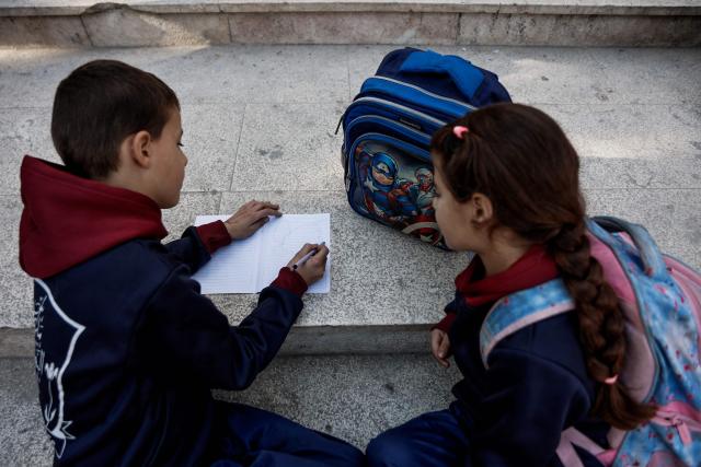 A young learner writes on a book during the start of classes at Latin Patriarchate School inside the Holy Family Catholic Church compound sheltering displaced Palestinians in Gaza City, on December 3, 2025. Israel said on December 3, it would open the Rafah crossing from Gaza to Egypt to allow residents to exit the Palestinian territory "in the coming days," but Egypt denied such a deal with Israel. (Photo by Omar AL-QATTAA / AFP)