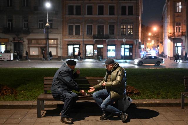 Two residents play cards in the street in Lviv on December 3, 2025, amid the Russian invasion of Ukraine. (Photo by Sergei GAPON / AFP)
