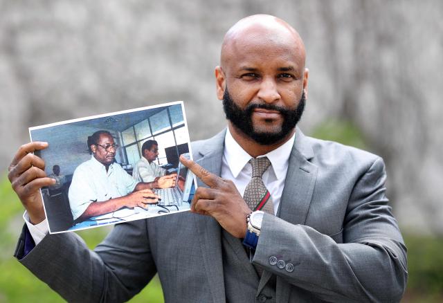 (FILES) Baba Hydara, son of the late Deyda Hydara, poses with a photo of his father on the sidelines of the trial against Gambian defendant Bai L. accused of crimes against humanity, murder and attempted murder in Celle, northern Germany on April 25, 2022. A former member of a Gambian death squad suspected of shooting AFP's correspondent in the west African country in 2004 was charged with murder on December 3, 2025, according to an AFP journalist who observed his arraignment in Banjul. Sanna Manjang, who was arrested on November 29 in neighbouring Senegal, was charged with two counts of murder for shooting longtime AFP journalist Deyda Hydara as well as another individual. (Photo by Ronny Hartmann / AFP)