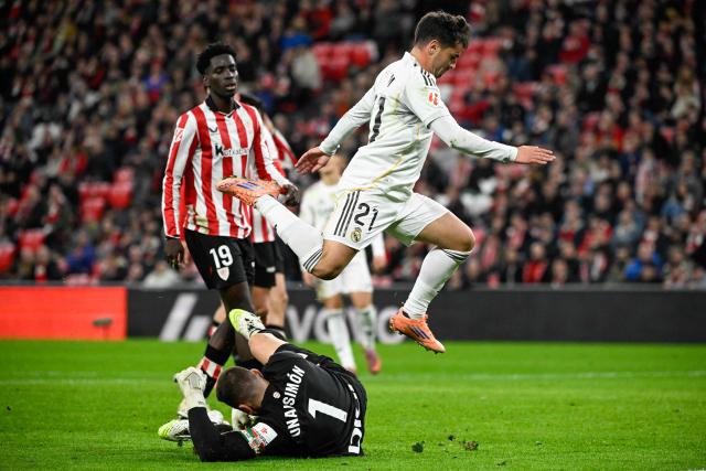 Real Madrid's Moroccan forward #21 Brahim Diaz (R) leaps over Athletic Bilbao's Spanish goalkeeper #01 Unai Simon during the Spanish league football match between Athletic Club Bilbao and Real Madrid CF at the San Mames stadium in Bilbao on December 3, 2025. (Photo by ANDER GILLENEA / AFP)