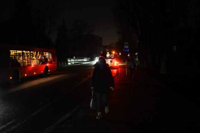 A woman walks along an unlit street during a power outage in Lviv on December 3, 2025, amid the Russian invasion of Ukraine. (Photo by Sergei GAPON / AFP)