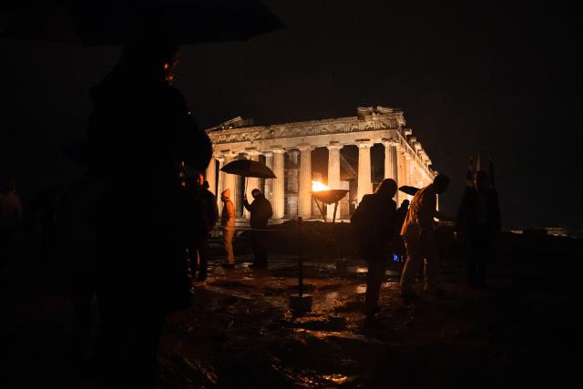 This photograph shows the cauldron with the Olympic flame in front of the ancient temple of the Parthenon atop the Acropolis hill during the Olympic torch relay in Athens on December 3, 2025. (Photo by Angelos TZORTZINIS / AFP)