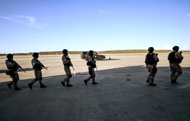Police officers patrol the tarmac before the arrival of an Eastern Airlines plane carrying Venezuelan migrants repatriated from the US at Simon Bolivar International Airport in Maiquetia, Venezuela, on December 3, 2025. Venezuela announced on December 2, 2025, that it had reauthorized flights carrying migrants deported by the US, days after suspending them due to President Donald Trump's demand that Venezuelan airspace be considered "closed." (Photo by Juan BARRETO / AFP)
