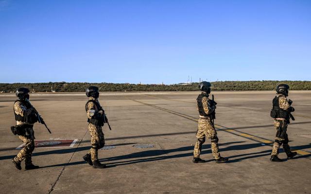 Police officers patrol the tarmac before the arrival of an Eastern Airlines plane carrying Venezuelan migrants repatriated from the US at Simon Bolivar International Airport in Maiquetia, Venezuela, on December 3, 2025. Venezuela announced on December 2, 2025, that it had reauthorized flights carrying migrants deported by the US, days after suspending them due to President Donald Trump's demand that Venezuelan airspace be considered "closed." (Photo by Juan BARRETO / AFP)