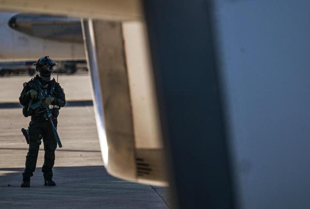 A police officer stands guard on the tarmac before the arrival of an Eastern Airlines plane carrying Venezuelan migrants repatriated from the US at Simon Bolivar International Airport in Maiquetia, Venezuela, on December 3, 2025. Venezuela announced on December 2, 2025, that it had reauthorized flights carrying migrants deported by the US, days after suspending them due to President Donald Trump's demand that Venezuelan airspace be considered "closed." (Photo by Juan BARRETO / AFP)