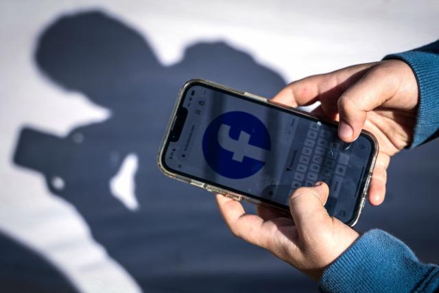 (FILES) This photo taken on October 24, 2025 shows a 14-year-old boy posing at his home near Gosford as he looks at social media on his mobile phone. Tech giant Meta said on December 4, 2025 it is starting to remove under-16s in Australia from Instagram, Threads and Facebook ahead of the country's world-first social media ban. (Photo by David GRAY / AFP)