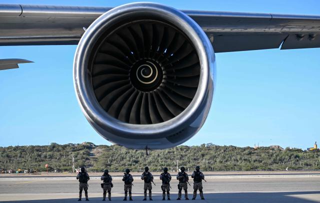 Police officers patrol the tarmac before the arrival of an Eastern Airlines plane carrying Venezuelan migrants repatriated from the US at Simon Bolivar International Airport in Maiquetia, Venezuela, on December 3, 2025. Venezuela announced on December 2, 2025, that it had reauthorized flights carrying migrants deported by the US, days after suspending them due to President Donald Trump's demand that Venezuelan airspace be considered "closed." (Photo by Juan BARRETO / AFP)