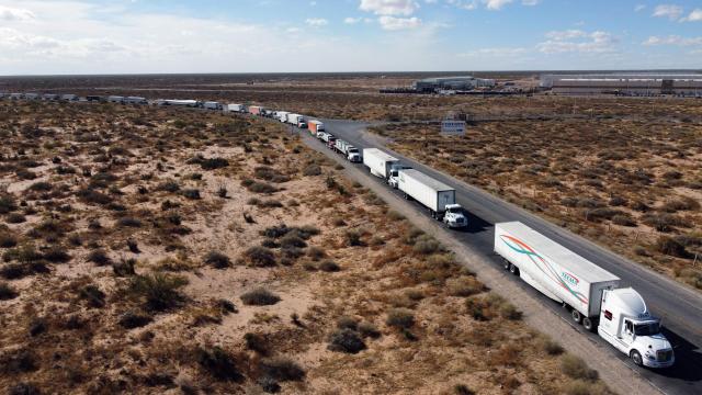 An aerial view shows trucks stopped at the commercial crossing into the United States due to a blockade caused by farmers' protest against Mexico's new water law at the Jeronimo-Santa Teresa International Bridge in Ciudad Juarez, Chihuahua state, Mexico, on December 3, 2025. Farmers from several states across the country protest against the approval of the national water law currently being debated in the Mexican Congress. (Photo by Herika Martinez / AFP)