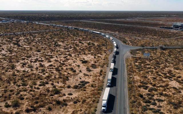An aerial view shows trucks stopped at the commercial crossing into the United States due to a blockade caused by farmers' protest against Mexico's new water law at the Jeronimo-Santa Teresa International Bridge in Ciudad Juarez, Chihuahua state, Mexico, on December 3, 2025. Farmers from several states across the country protest against the approval of the national water law currently being debated in the Mexican Congress. (Photo by Herika Martinez / AFP)
