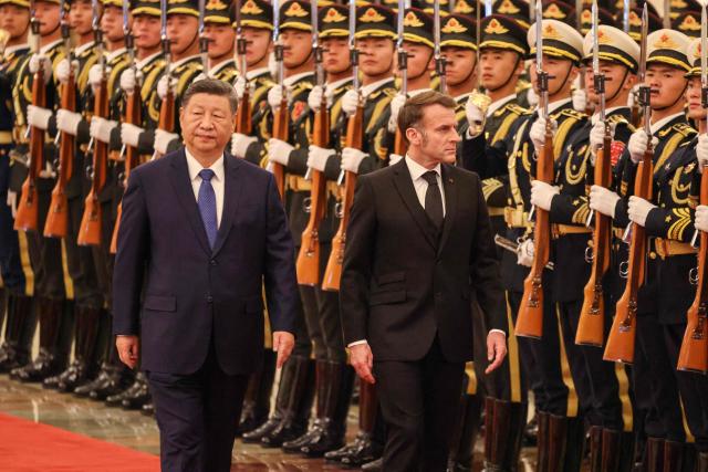 China's President Xi Jinping (L) and France's President Emmanuel Macron review an honour guard during a welcome ceremony at the Great Hall of the People in Beijing on December 4, 2025. (Photo by Ludovic MARIN / POOL / AFP)