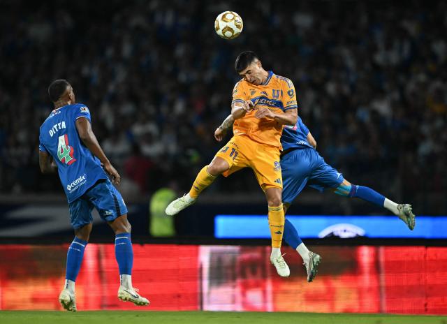 Tigres' Argentine midfielder #11 Juan Brunetta and Cruz Azul's defender #02 Jorge Sanchez (back) jump to head the ball past Cruz Azul's Colombian defender #04 Willer Ditta during the first leg of the Liga MX Apertura semifinal football match between Cruz Azul and Tigres at Banorte Stadium in Mexico City on December 3, 2025. (Photo by CARL DE SOUZA / AFP)