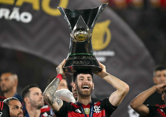 Flamengo's defender #04 Leo Pereira lifts the Brasileirao trophy after winning the Brasileirao Serie A football match between Flamengo and Ceara at Maracana Stadium in Rio de Janeiro, Brazil, on December 3, 2025. (Photo by Mauro PIMENTEL / AFP)