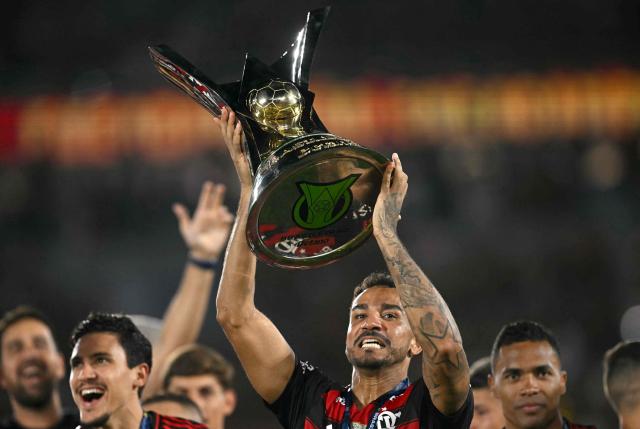 Flamengo's defender #13 Danilo lifts the Brasileirao trophy after winning the Brasileirao Serie A football match between Flamengo and Ceara at Maracana Stadium in Rio de Janeiro, Brazil, on December 3, 2025. (Photo by Mauro PIMENTEL / AFP)