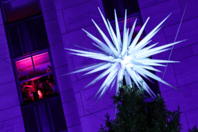 People watch from their window the Rockefeller Center Christmas Tree Lighting in New York City on December 3, 2025. (Photo by CHARLY TRIBALLEAU / AFP)