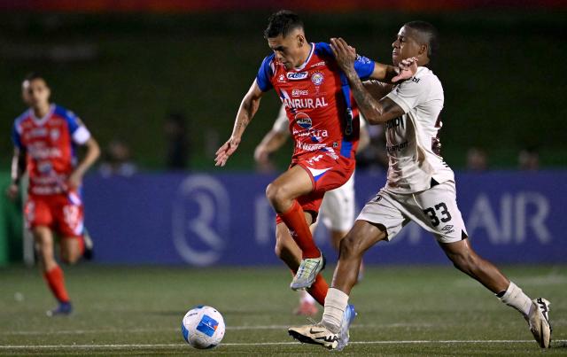 Xelaju's Paraguayan defender #04 Manuel Romero and Alajuelense's Colombian forward #33 Jeison Lucumi fight for the ball during the second leg of the CONCACAF Central American Cup final football match between Guatemala's Xelaju and Costa Rica's Alajuelense at Mario Camposeco Stadium in Quetzaltenango, Guatemala, on December 3, 2025. (Photo by JOHAN ORDONEZ / AFP)