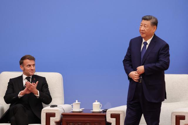 France's President Emmanuel Macron (L) applauds as China's President Xi Jinping walks to the podium to deliver a speech during the 7th formal meeting of the Franco-Chinese Business Council in Beijing on December 4, 2025. (Photo by Ludovic MARIN / POOL / AFP)