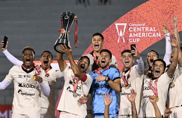 Alajuelense players celebrate with the trophy after winning the championship on penalty shoot-out of the CONCACAF Central American Cup final football match between Guatemala's Xelaju and Costa Rica's Alajuelense at Mario Camposeco Stadium in Quetzaltenango, Guatemala, on December 3, 2025. (Photo by JOHAN ORDONEZ / AFP)