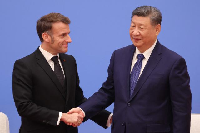 France's President Emmanuel Macron (L) and China's President Xi Jinping shake hands during the 7th formal meeting of the Franco-Chinese Business Council in Beijing on December 4, 2025. (Photo by Ludovic MARIN / POOL / AFP)