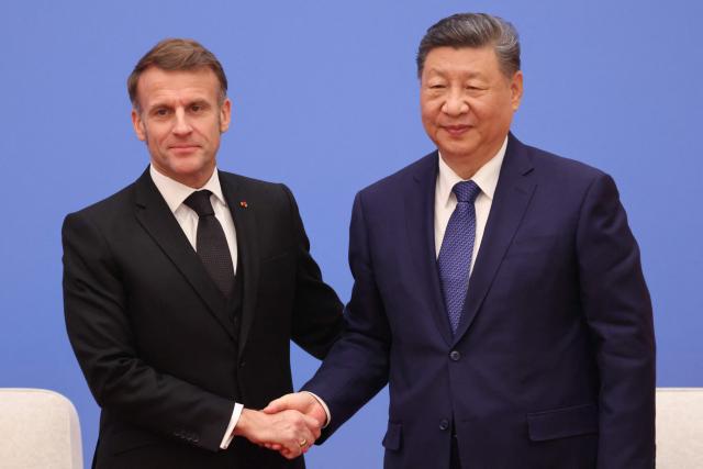 France's President Emmanuel Macron (L) and China's President Xi Jinping shake hands during the 7th formal meeting of the Franco-Chinese Business Council in Beijing on December 4, 2025. (Photo by Ludovic MARIN / POOL / AFP)