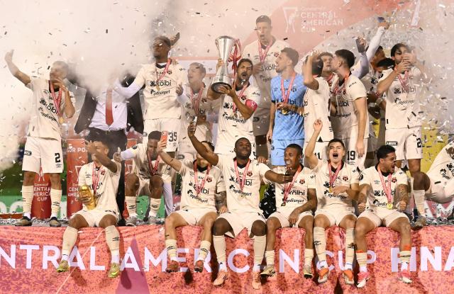 Alajuelense players celebrate with the trophy after winning the championship on penalty shoot-out of the CONCACAF Central American Cup final football match between Guatemala's Xelaju and Costa Rica's Alajuelense at Mario Camposeco Stadium in Quetzaltenango, Guatemala, on December 3, 2025. (Photo by JOHAN ORDONEZ / AFP)
