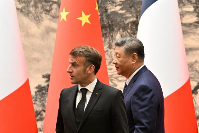 China's President Xi Jinping (R) and France's President Emmanuel Macron walk after delivering a joint statement to the press following meetings and a signing ceremony for agreements at the Great Hall of the People in Beijing on December 4, 2025. (Photo by Adek BERRY and ADEK BERRY / POOL / AFP)