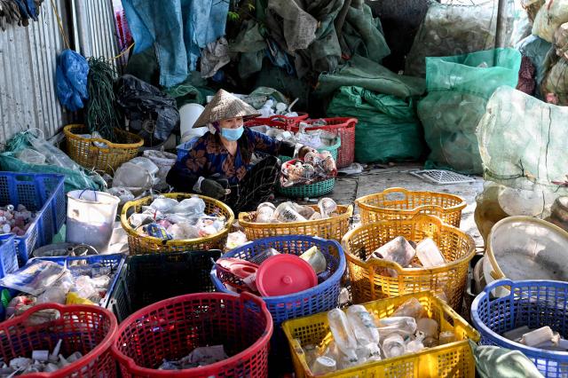 This photo taken on November 25, 2025 shows a woman sorting plastic waste in Hanoi. (Photo by Nhac NGUYEN / AFP)