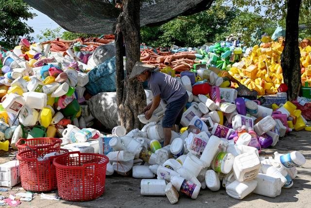 This photo taken on November 25, 2025, shows a man working at a plastic waste dump in a village on the outskirts of Hanoi. (Photo by Nhac NGUYEN / AFP)