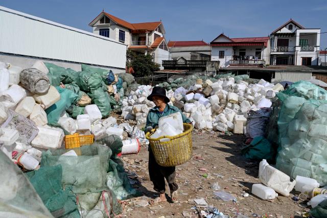 This photo taken on November 25, 2025, shows a man working at a plastic waste dump in a village on the outskirts of Hanoi. (Photo by Nhac NGUYEN / AFP)