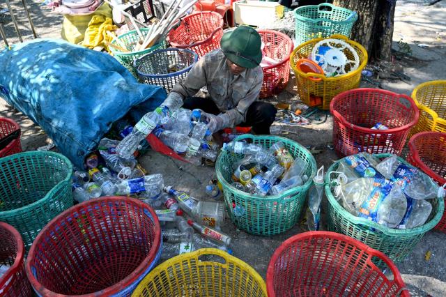 This photo taken on November 25, 2025, shows a man working at a plastic waste dump in a village on the outskirts of Hanoi. (Photo by Nhac NGUYEN / AFP)